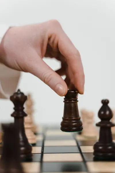 A hand placing a wooden rook on a chessboard