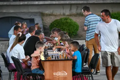Children playing chess at a community event with Slaven Pastar